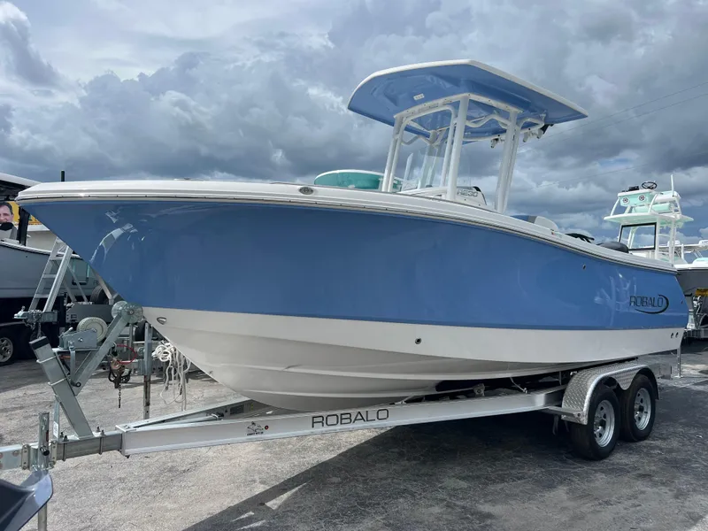 Slide: The Image of 2024 Robalo R230 Center Console boat on a trailer under cloudy skies. - 0