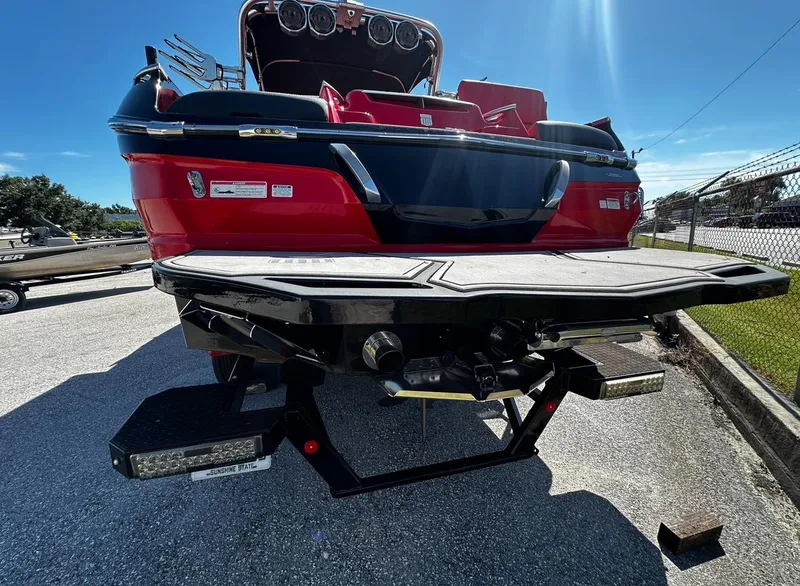 Slide: The Image of 2020 MasterCraft X24 boat rear view with swim platform and red exterior. - 2
