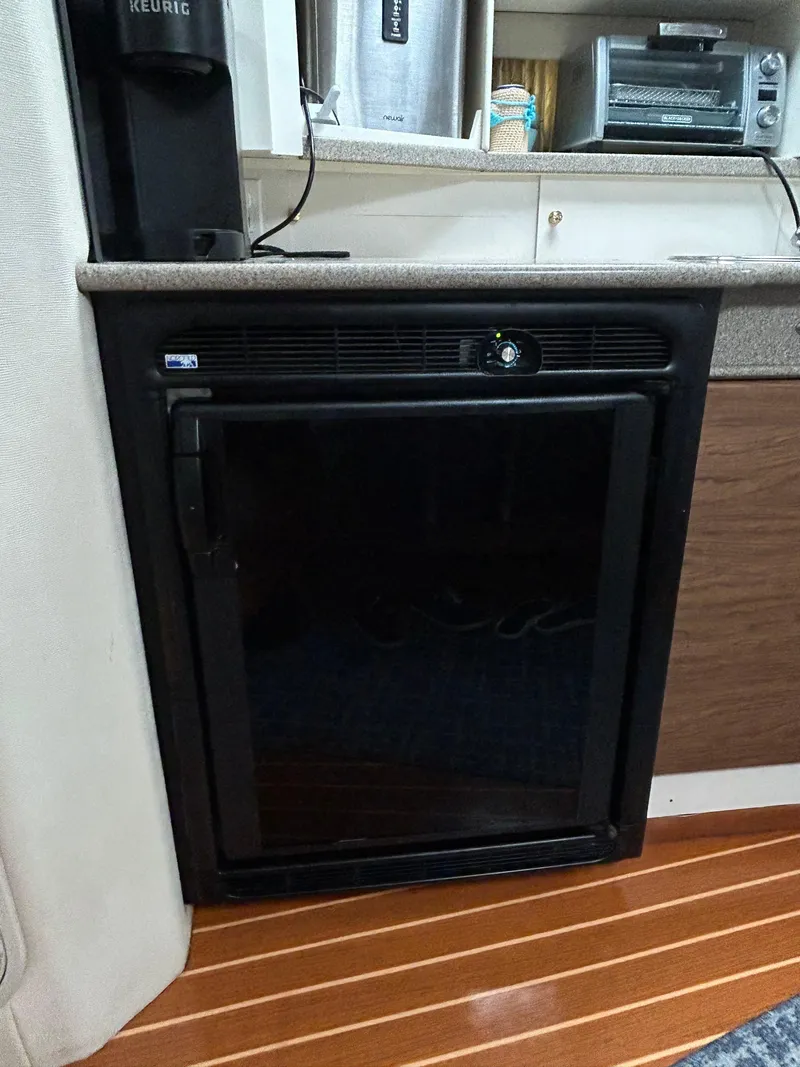 Slide: The Image of Compact refrigerator in 2000 Formula 34 PC boat interior, featuring wood flooring and countertop. - 33