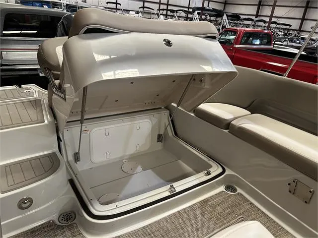 Slide: The Image of 2018 Crownline E21X boat with open storage compartment in a showroom. - 15