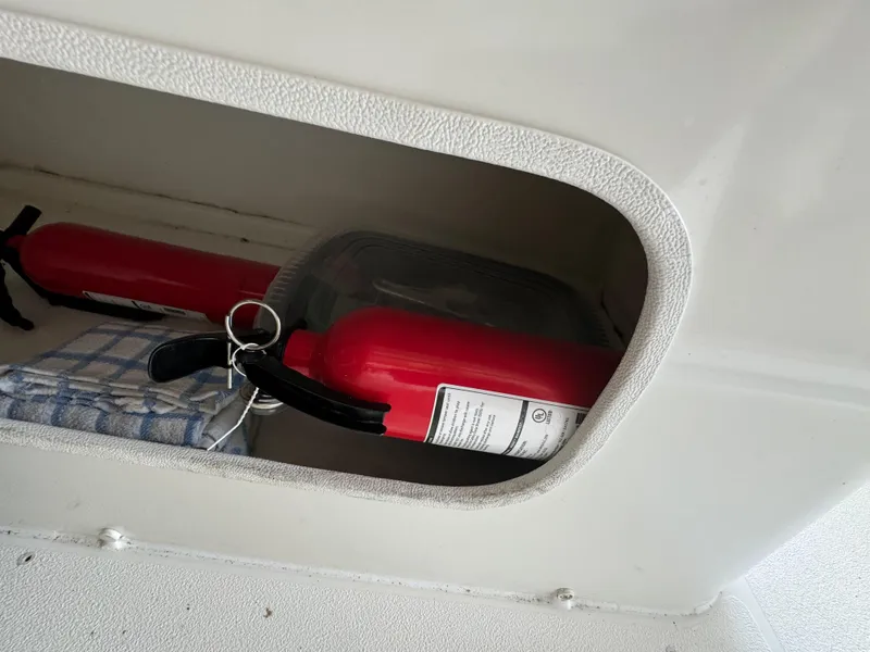 Slide: The Image of Fire extinguishers and towel in storage compartment of 2004 Larson 330 boat. - 28