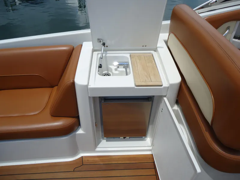 Slide: The Image of 2009 Chris-Craft Corsair 36 boat interior with sink, fridge, and brown leather seating. - 15