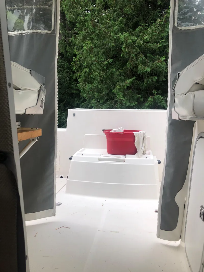 Slide: The Image of 1997 Bayliner Ciera 2452 Express boat interior with red bucket, surrounded by greenery. - 13