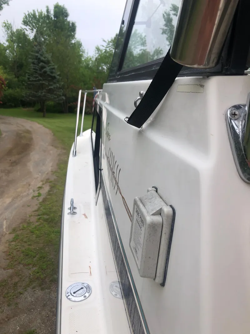 Slide: The Image of 1997 Bayliner Ciera 2452 Express boat side view with lush greenery background. - 29