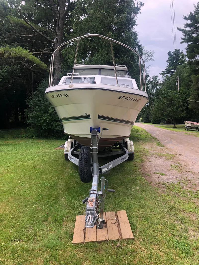 Slide: The Image of 1997 Bayliner Ciera 2452 Express boat on trailer, parked on grassy area. - 4