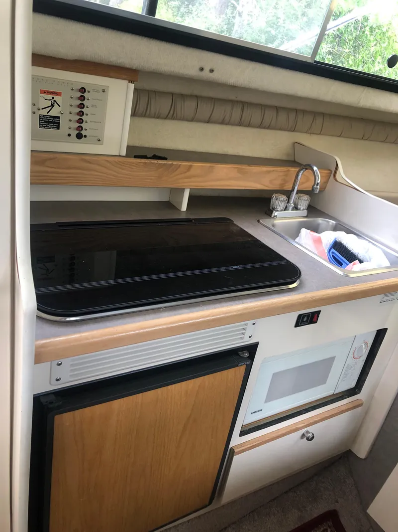 Slide: The Image of 1997 Bayliner Ciera 2452 Express kitchen area with stove, sink, and microwave. - 44