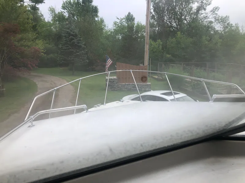 Slide: The Image of 1997 Bayliner Ciera 2452 Express boat on a driveway with trees and an American flag. - 27