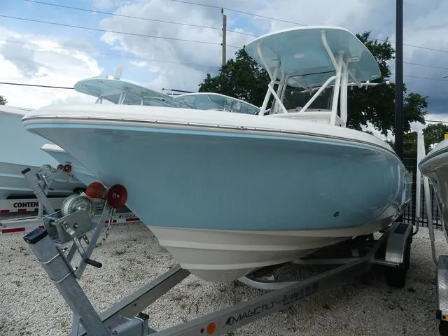 Slide: The Image of 2025 Pioneer Islander 222 boat on a trailer, light blue hull, parked outdoors. - 4