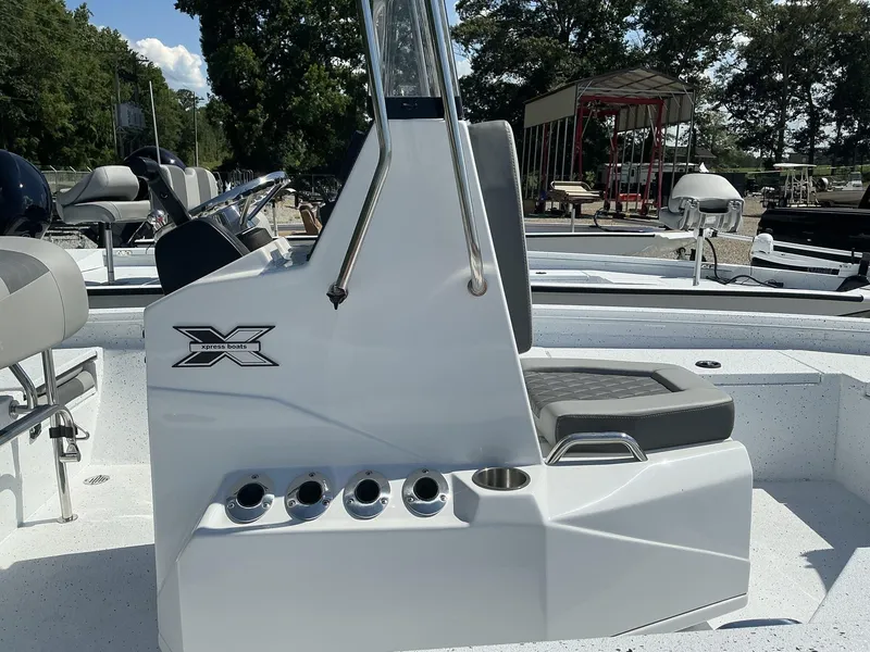 Slide: The Image of 2025 Xpress H20B NEW CONSOLE boat with seating and steering wheel, docked outdoors. - 5