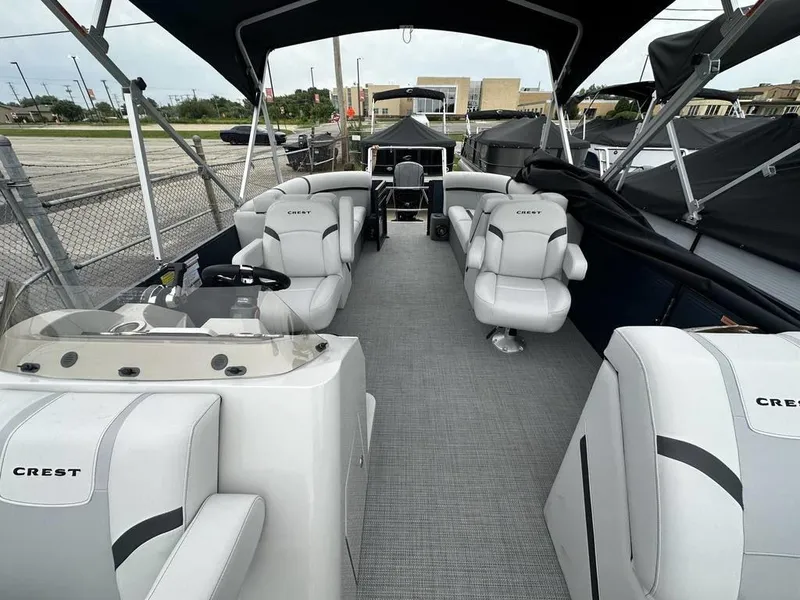 Slide: The Image of 2024 Crest Classic LX 220 SLC pontoon boat interior with white seating and black canopy. - 6