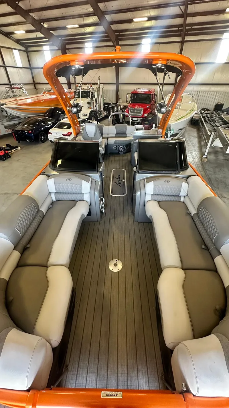 Slide: The Image of 2023 Avalon Excalibur Elite Windshield boat interior with spacious seating in a showroom. - 14