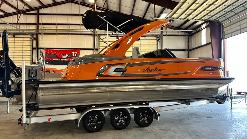 Slide: The Image of 2023 Avalon Excalibur Elite Windshield boat in a warehouse. - 4
