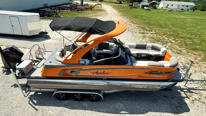 Slide: The Image of 2023 Avalon Excalibur Elite Windshield boat with orange accents and black canopy. - 5