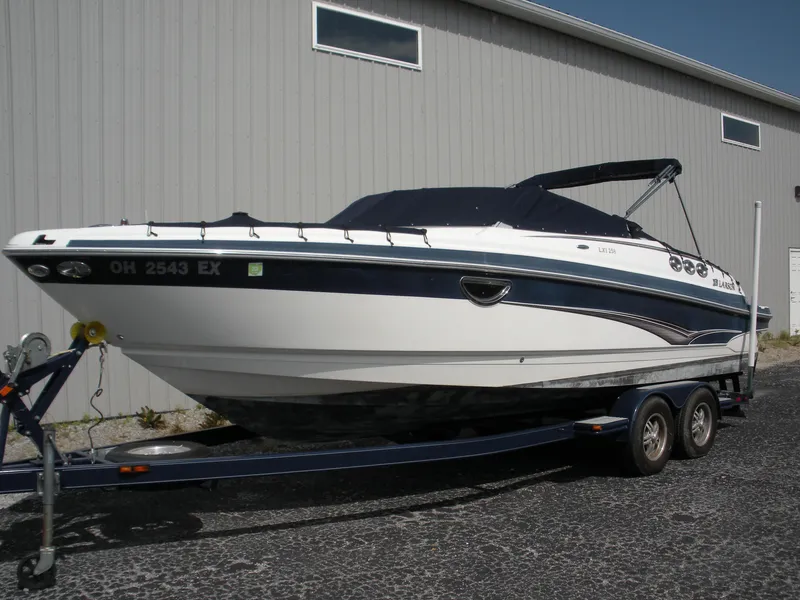The Image of 2009 Larson LXi 258 boat on a trailer outside a warehouse. - 0