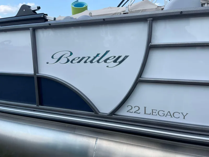 Slide: The Image of 2025 Bentley Pontoons Legacy 220 Swingback side view with logo and model name. - 2
