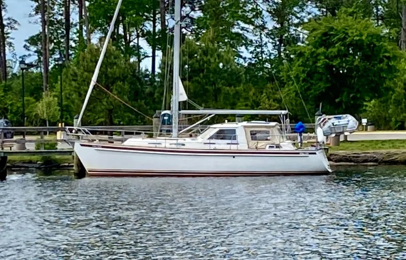 Slide: The Image of Sailboat Vilm 116, 2002 model, docked by lush greenery and calm waters. - 43