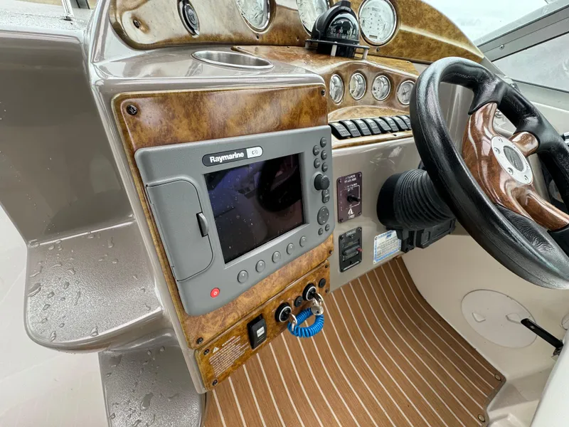 Slide: The Image of 2006 Rinker 320 Express Cruiser helm with Raymarine GPS and woodgrain dashboard. - 13