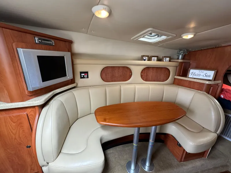 Slide: The Image of 2006 Rinker 320 Express Cruiser interior with curved leather seating and wooden table. - 16