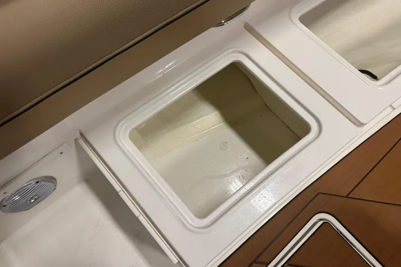 Slide: The Image of 2023 Bayliner DX 2000 boat storage compartments with cushioned seating and wood-style flooring. - 16