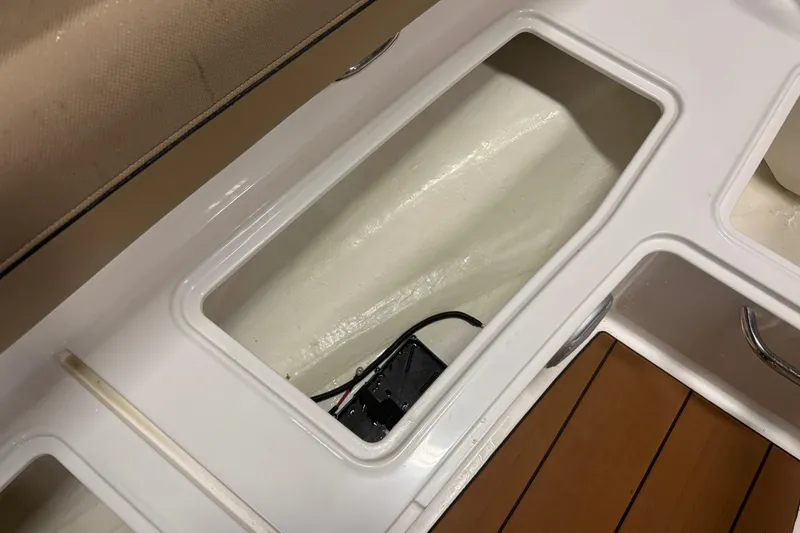 Slide: The Image of 2023 Bayliner DX 2000 boat storage compartment with wiring, white and brown interior. - 17
