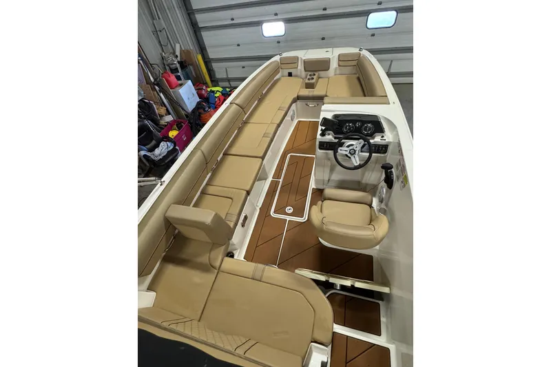 Slide: The Image of 2023 Bayliner DX 2000 boat interior with tan seating and modern dashboard in a garage. - 29