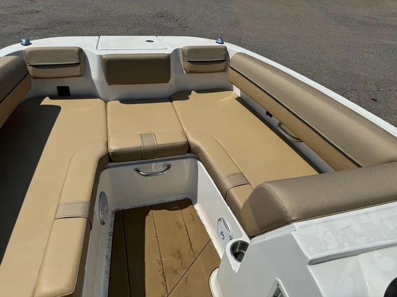 Slide: The Image of 2023 Bayliner DX 2000 boat interior with beige cushioned seating and brown flooring. - 8
