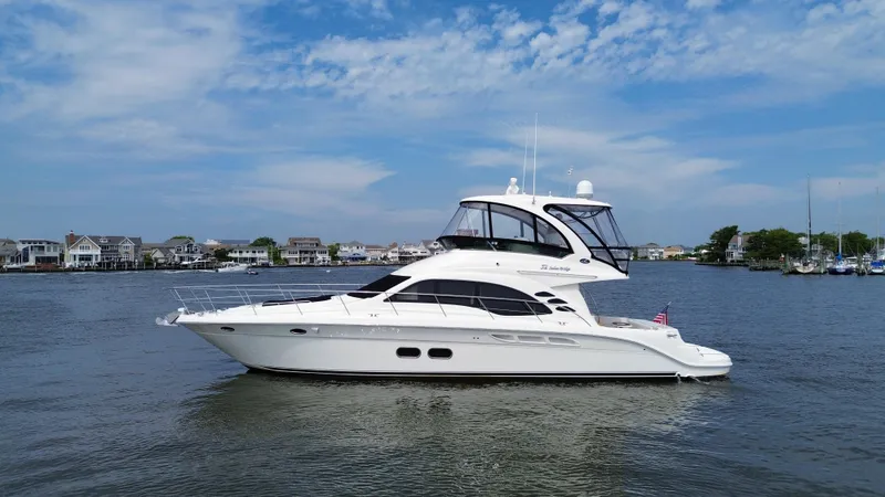 Slide: The Image of 2007 Sea Ray 52 Sedan Bridge yacht on calm water with a scenic background. - 10