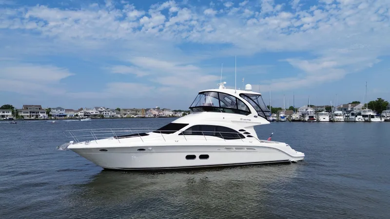Slide: The Image of 2007 Sea Ray 52 Sedan Bridge yacht on calm water with marina background. - 11