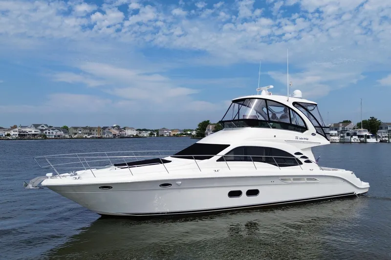 Slide: The Image of 2007 Sea Ray 52 Sedan Bridge yacht on calm water with a scenic background. - 12