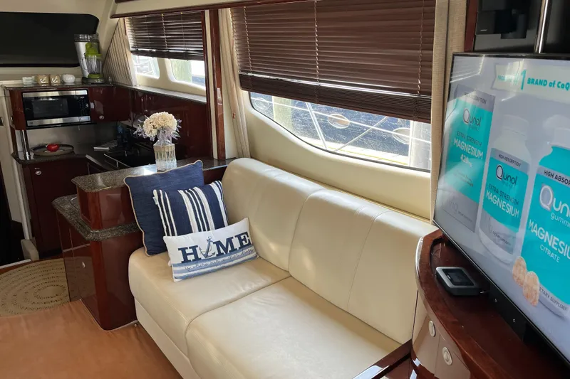 Slide: The Image of Interior of 2007 Sea Ray 52 Sedan Bridge with white leather sofa, TV, and kitchen area. - 48