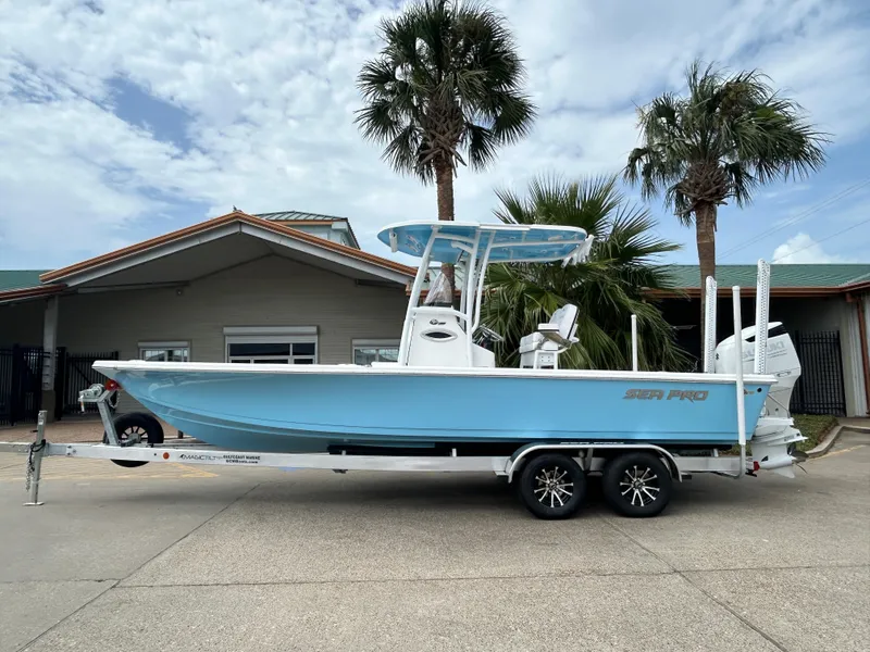 The Image of 2024 Sea Pro 250 DLX boat on a trailer, parked near palm trees. - 0