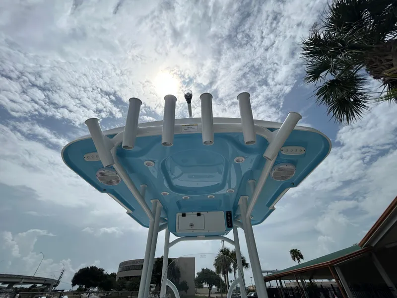 Slide: The Image of 2024 Sea Pro 250 DLX boat with T-top and rod holders under a cloudy sky. - 17