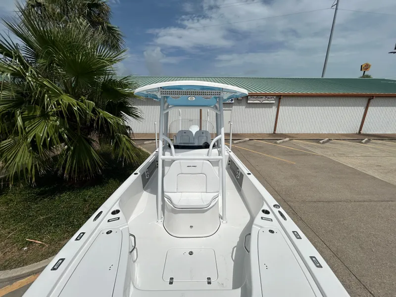 Slide: The Image of 2024 Sea Pro 250 DLX boat with T-top, docked near palm tree and building. - 24