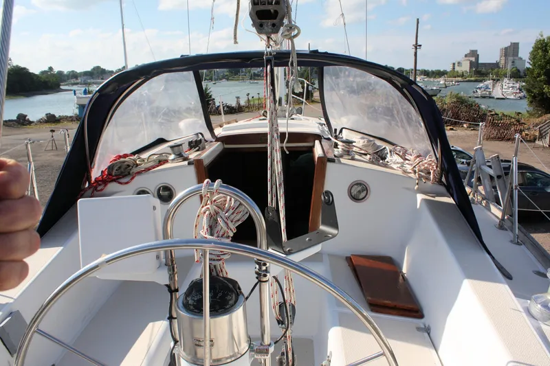 Slide: The Image of 1988 Tartan 34-2 Scheel Keel sailboat cockpit with steering wheel and marina view. - 10