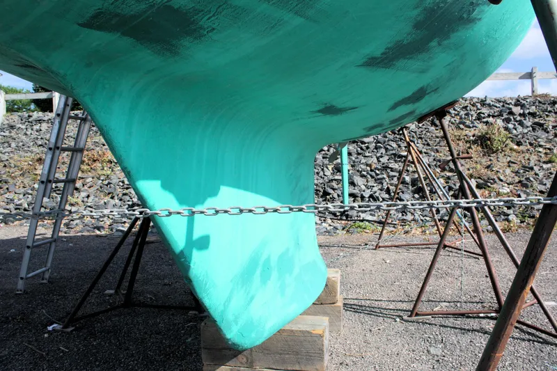 Slide: The Image of Keel of 1988 Tartan 34-2 Scheel, turquoise, supported by stands and chain. - 15