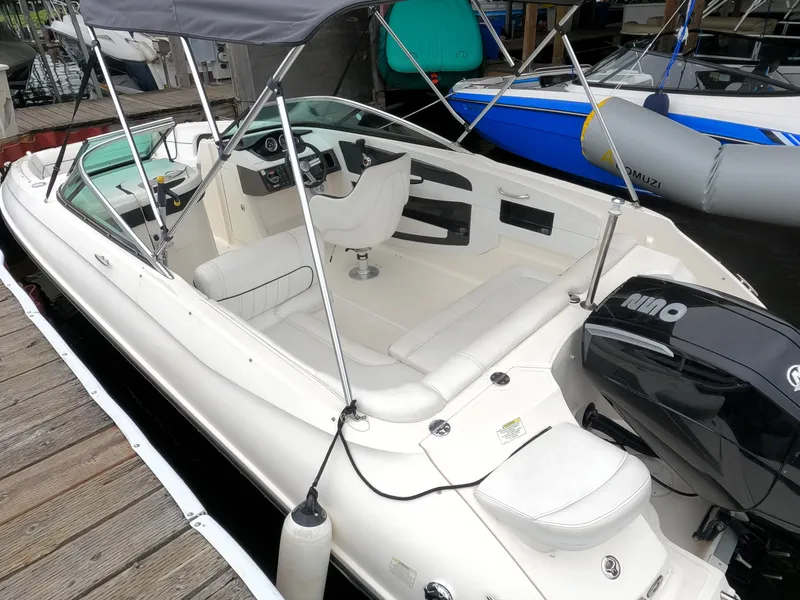 Slide: The Image of 2014 Sea Ray 240 Sundeck Outboard boat docked, featuring spacious seating and a Bimini top. - 13