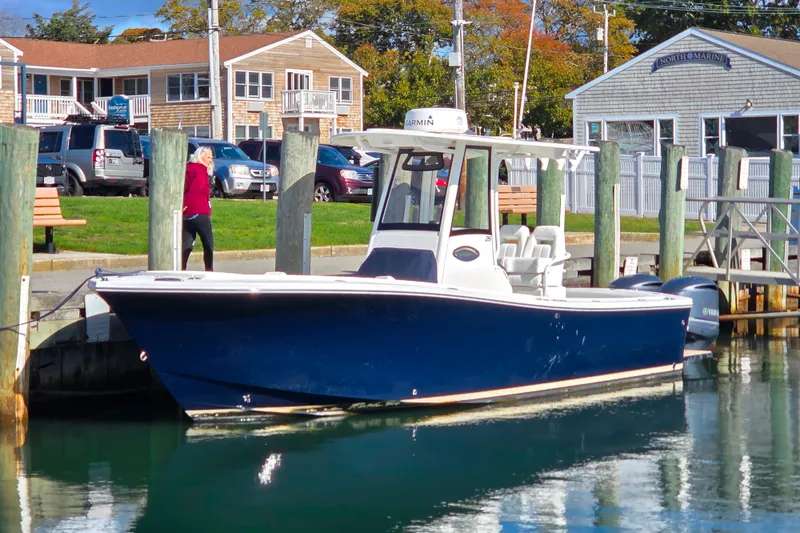 The Image of 2020 Regulator 25 boat docked in marina, blue hull, clear sky background. - 0