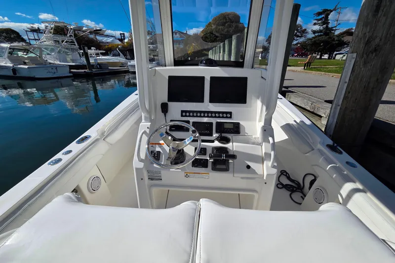 Slide: The Image of 2020 Regulator 25 boat cockpit with steering wheel and control panel, docked by the water. - 20