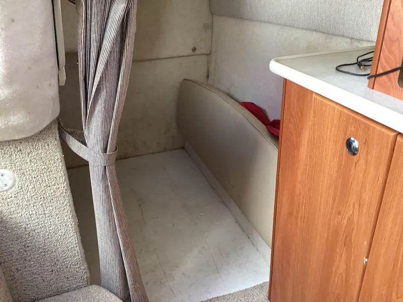 Slide: The Image of Interior cabin of a 2004 Bayliner 2655 Ciera boat with striped curtain and wooden cabinet. - 27