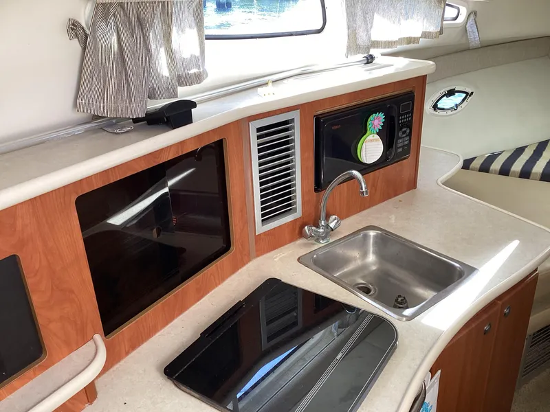 Slide: The Image of 2004 Bayliner 2655 Ciera boat interior kitchen with sink, microwave, and stove. - 31