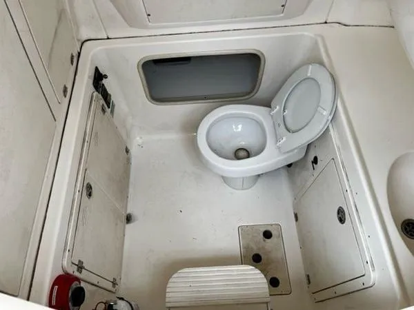 Slide: The Image of 2004 Boston Whaler 320 Outrage boat bathroom with toilet and storage compartments. - 26