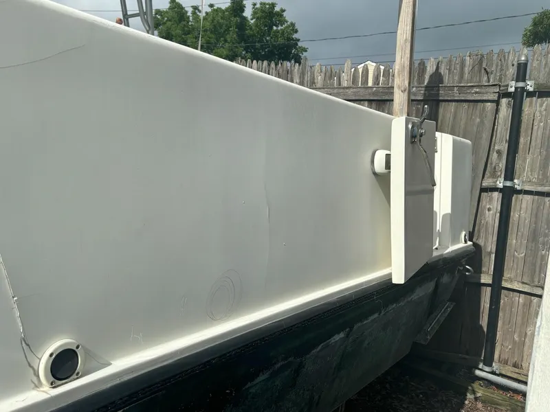 Slide: The Image of 1998 Contender 35 Express boat side view, parked near wooden fence. - 8