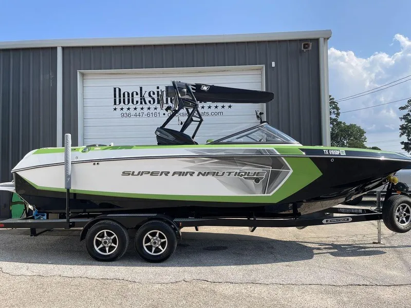 Slide: The Image of 2016 Nautique G25 Super Air boat in green and white, parked on a trailer. - 0