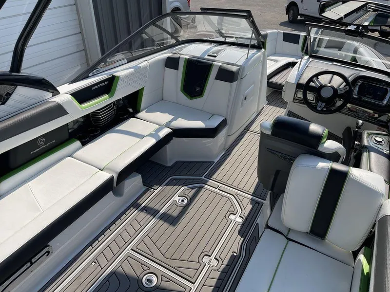 Slide: The Image of 2016 Nautique G25 boat interior with white and black seating, green accents, and modern dashboard. - 4