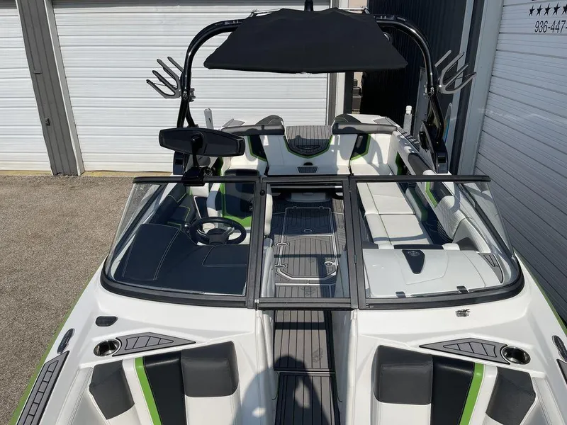 Slide: The Image of 2016 Nautique G25 boat interior with black and green accents, docked in a marina. - 8