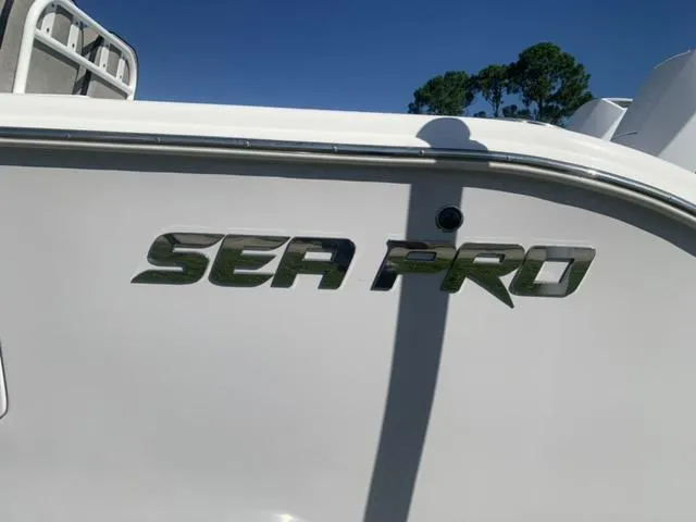 Slide: The Image of 2024 Sea Pro 262 CC boat logo on white hull under clear blue sky. - 12