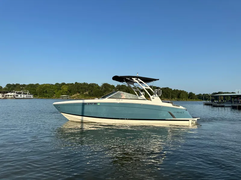 Slide: The Image of 2022 Cobalt R6 Surf boat on a calm lake under clear blue skies. - 2