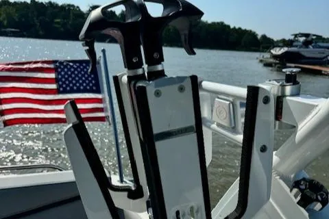 Slide: The Image of 2022 Cobalt R6 Surf boat with American flag and wakeboard rack on a lake. - 20