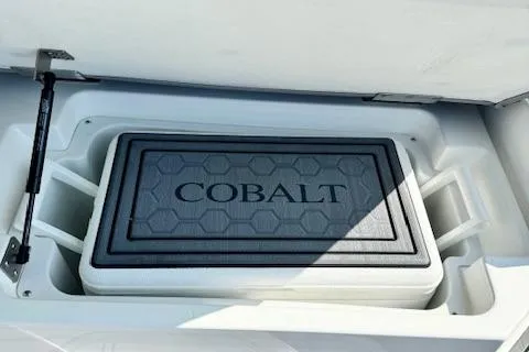 Slide: The Image of 2022 Cobalt R6 Surf boat cooler compartment with Cobalt-branded cooler. - 26