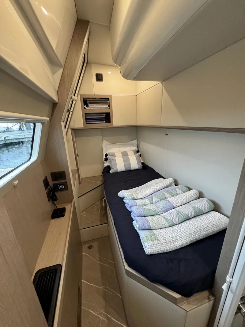 Slide: The Image of 2023 Absolute 52 Navetta cabin with single bed, window, and storage shelves. - 36